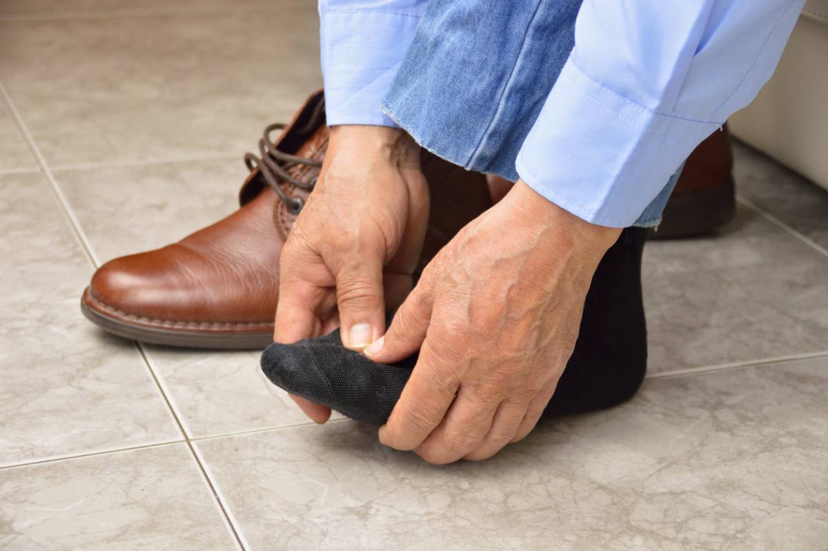 An unrecognizable man suffering with foot cramp in the room stock image